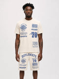 Man wearing cream Diplomats Bike Life matching t-shirt and shorts set with racing-inspired graphics