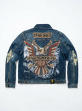 A blue denim jacket shown from the back, featuring a large patriotic eagle graphic with the words 'THE SET' and 'DIPLOMATS' in gold lettering, along with distressed details on the sleeves.
