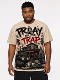 A man wearing a beige graphic t-shirt with a detailed black and red print that reads 'PROAY FOR THE TRAP' above an illustration of a haunted house and a car, set against a plain light gray background.