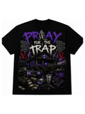 A black short-sleeve graphic t-shirt featuring a detailed street-style illustration with the text 'PRAY FOR THE TRAP' in purple and white, alongside a car, cash, and purple lightning accents.