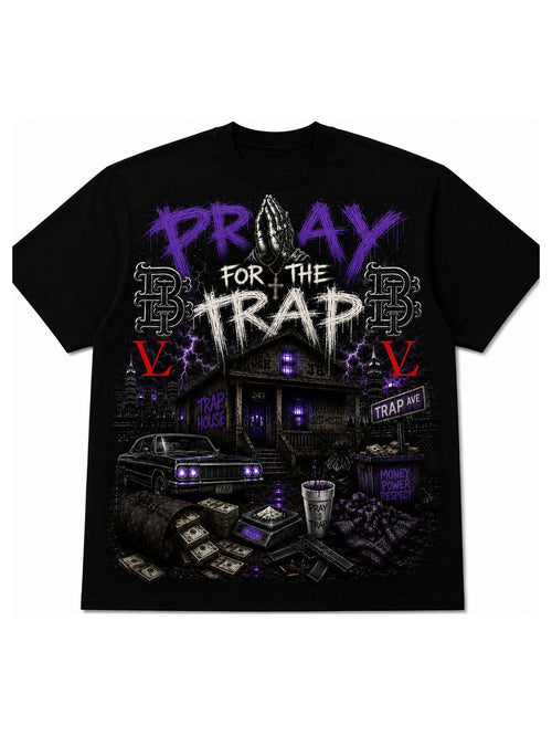A black short-sleeve graphic t-shirt featuring a detailed street-style illustration with the text 'PRAY FOR THE TRAP' in purple and white, alongside a car, cash, and purple lightning accents.